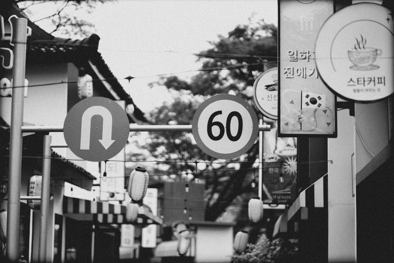 Black and White Photo of Signs between Buildings in City