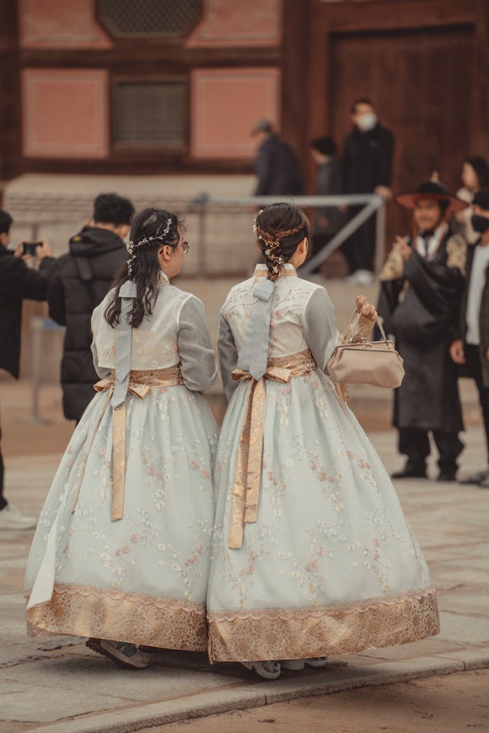 Back View of Women in Traditional Clothing Walking near a Building